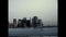 A vintage film shot looking back from a boat toward the New York City skyline from the 1970s