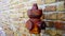 Vintage fire hydrant of red colour with rusty valve by wall