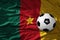 Vintage football ball on the waveing national flag of cameroon background. 3D illustration