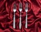Vintage forks on a red silk tablecloth. Top view.