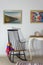 Vintage Furniture: Rocking chair and antique desktop clock on old style vintage table on background of off white wall