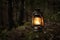 Vintage gasoline oil lantern lamp burning with a soft glow light in an dark forest / wood.