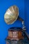 Vintage gramophone. Old record players take on the blue background. Golden gramophone with disk on wooden box isolated on blue bac