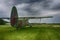 Vintage green biplane parked in a lush green field