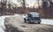 Vintage green classic car drives down old winding road in winter