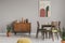Vintage grey dining room with abstract paintings and wooden cupboard