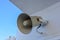 Vintage horn speaker for public announcements. Grey technological device for sound amplifying, background of metal wall and blue s