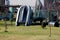 Vintage inflatable rubber boat next to barrel like weight left in family house backyard surrounded with wire fence and backyard