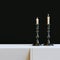 Vintage iron candlestick with burning candles in black interior.