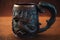 a vintage iron mug, adorned with intricate scrollwork and a handle in the shape of a dragon