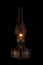 Vintage kerosene lamp burning on black background. Glass old oil lamp