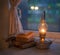 Vintage kerosene lamp with fire on a blurred background of the window and curtains with a book and glasses