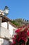 Vintage lantern on white stucco house with red bougainvillea flowers in bloom and ancient town wall of Obidos, Portuga