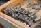 Vintage lead letterpress printing blocks against a weathered wooden drawer background with bokeh