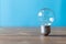 Vintage light bulb stands free and vertically on a dark wooden table. The photo has free space and the background is blue