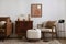 Vintage living room interior with mock up poster frame, wooden sideboard, boucle armchair, stylish white pouf, books, brown pillow