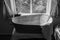 A vintage metal bath tub in the window of a house, with a towel draped over the end of the tub