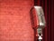 Vintage metal microphone against red curtain on empty theatre stage. 3d render