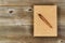 Vintage metal pen and burlap covered notepad on old wooden desktop