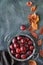 Vintage metal plate with red plums and scattered red and orange Autumn leaves, flat lay with text space