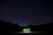 Vintage motorhome on the beach in night time. Dark starry sky with shining stars. Camper lifestyle