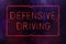 Vintage Neon Defensive Driving Sign in Rainy Window