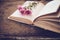 Vintage novel books with bouquet of flowers on old wood background