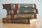 Vintage old books in four volumes stacked on the wooden surface