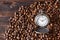 Vintage opened pocket watch among coffee beans on brown wooden table. Morning coffee,10 o`clock.