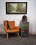 Vintage orange armchair, colorful cupboard, old radio and hanged painting