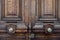 Vintage ornate metal doorknobs of aged wooden double door in Paris France. Symmetric handles and dark wood texture of old door.