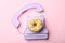 Vintage phone made with donut on pink background