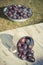 Vintage photo, Plums spill out of metallic mug on wooden table in garden on sunny day