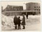 Vintage photo shows girls and boy talk on street in winter. Socialist mosaic on background.