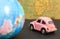 Vintage pink car and globe on map background, travel concept