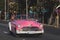 Vintage pink car on a street in a quaint city at daytime