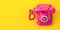 Vintage pink telephone on yellow background