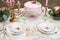 Vintage plates with roses on a table with cutlery and glasses. Pink cake with rose