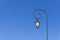 Vintage pole light, white glass and black body lamp on black steel with circle on the top, under deep blue sky background; object