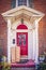 Vintage porch with red door with leaded glass window and pillars with large cardboard delivered packages sitting on proch