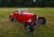 Vintage Red 1932 Ford Coupe Customised Hot rod isolated on grass.