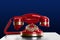 Vintage red corded telephone on table against blue background