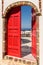 Vintage red door ajar and ocean view in Santorini, Greece.