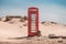 A vintage red telephone box in the sand dunes of a deserted beach at Studland, near Sandbanks, Dorset, England, UK