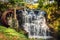 Vintage red waterwheel with waterfall in Glenariff Forest Park