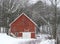 Vintage red wood barn in country woods snowstorm