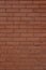 Vintage reddish brown exterior brick wall background with a scuffed appearance