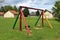 Vintage retro colorful wooden outdoor public playground equipment in shape of swing in front of abandoned military complex