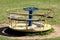 Vintage retro partially rusted outdoor public playground equipment made of metal with faded colors and wood in shape of roundabout