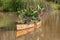 Vintage rowboat filled with flowers and tropical plants floating on pond with reflection in water